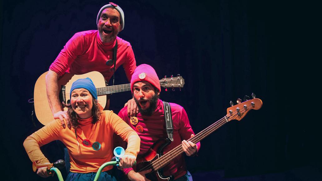 Imatge d'una escena de l'espectacle amb tres personatges: una noia amb una bicicleta i els altres dos amb una guitarra